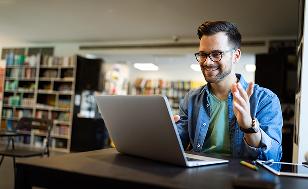 Smiling man using laptop in library