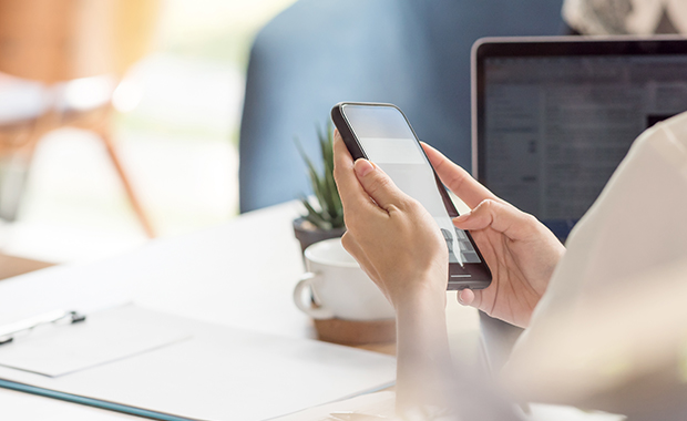 Woman holds iPhone above pad of paper