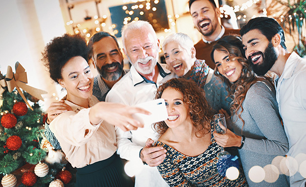 Group of smiling people take selfie at holiday party