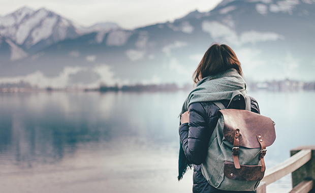 Back view of woman wearing backpack looking at winter landscape