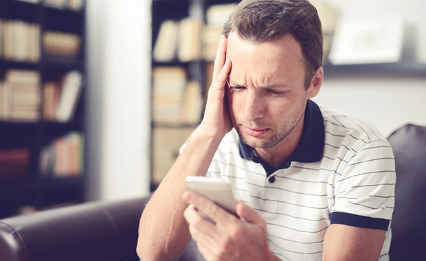 Man looks at smartphone with concerned experssion