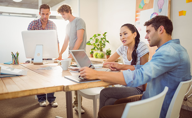 Group of young professionals at table looking at computers