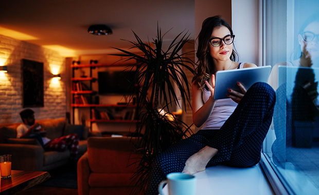 Woman writing in diary at café table with laptop and phone