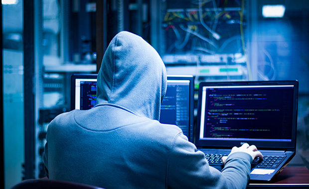 Back view of person wearing hoodie in front of computer screens