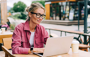 Woman working on laptop outdoors and smiling