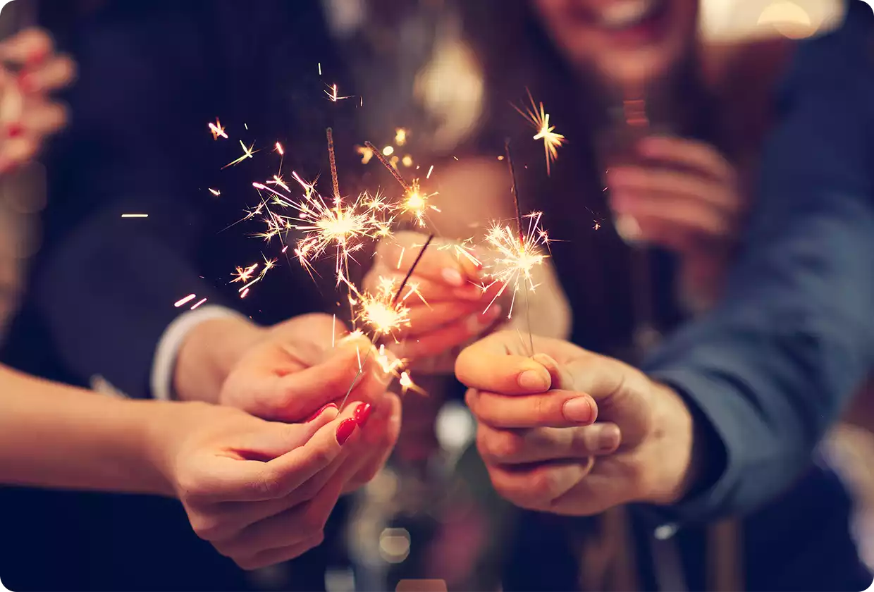 A group of people holding sparklers while celebrating together.