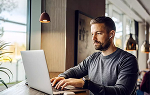 Man with laptop in café near window