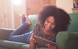 Smiling woman lying on couch reading from iPad