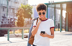 Smiling woman outdoors looking at smartphone