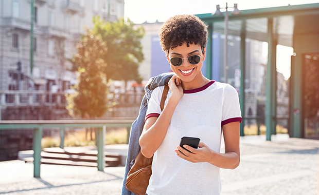 Smiling woman outdoors looking at smartphone