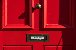 Closeup of mail slot on red door with sign “No junk mail”