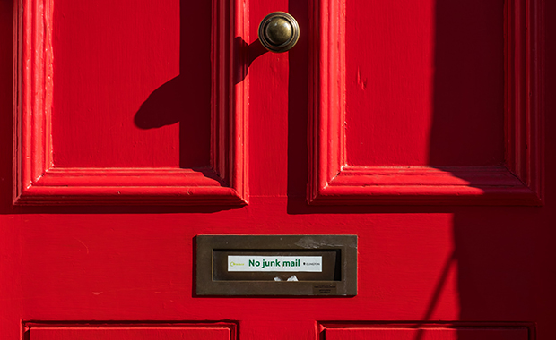 Closeup of mail slot on red door with sign “No junk mail”