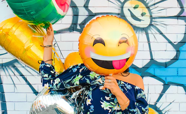 Woman holding a balloon with a  smiley face