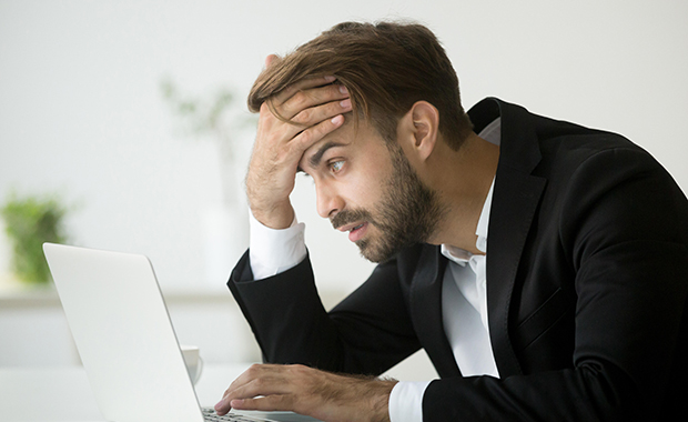 Stressed businessman looks at his laptop