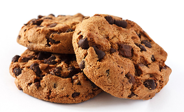 Three chocolate chip cookies stacked against a white background