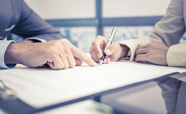 Hands pointing at clipboard with document that is being signed