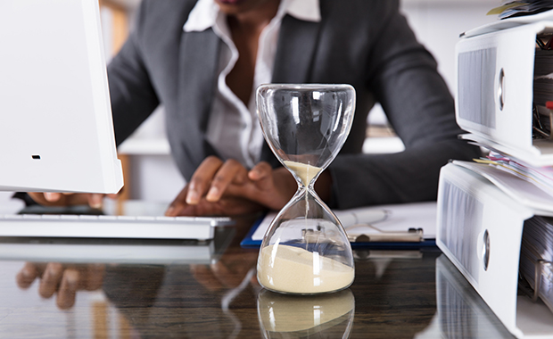 Close-up of hourglass in front of businessperson working in office