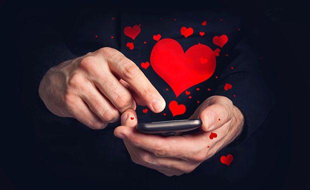 Man’s hands typing love messages on a smartphone