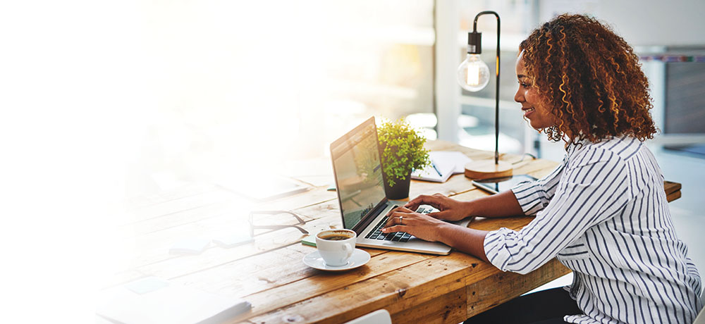 woman sitting at desk typing on laptop