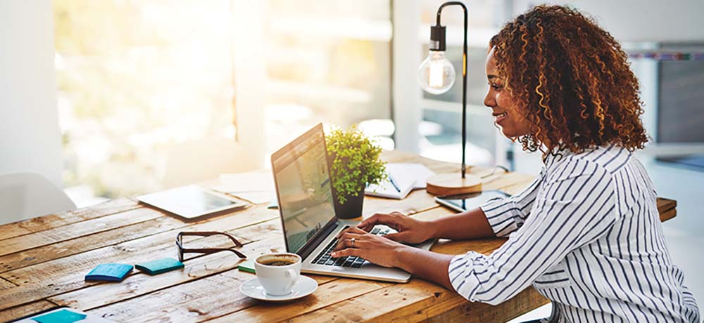 woman sitting at desk typing on laptop