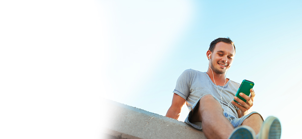 man with smartphone and headphones on a rooftop