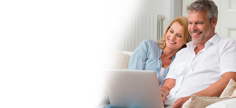 smiling couple uses laptop to check email