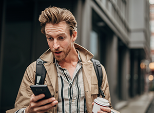Man holding smartphone with shocked expression
