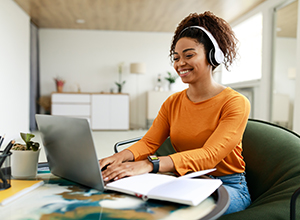 Smiling woman wearning headphones works at laptop