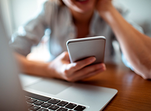 Hand holding smartphone next to laptop keyboard