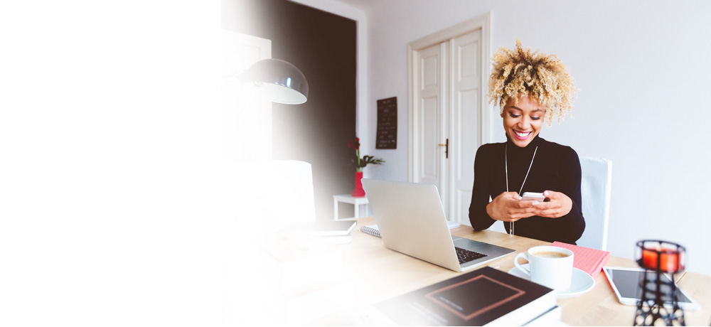 smiling woman with smartphone and laptop in her office