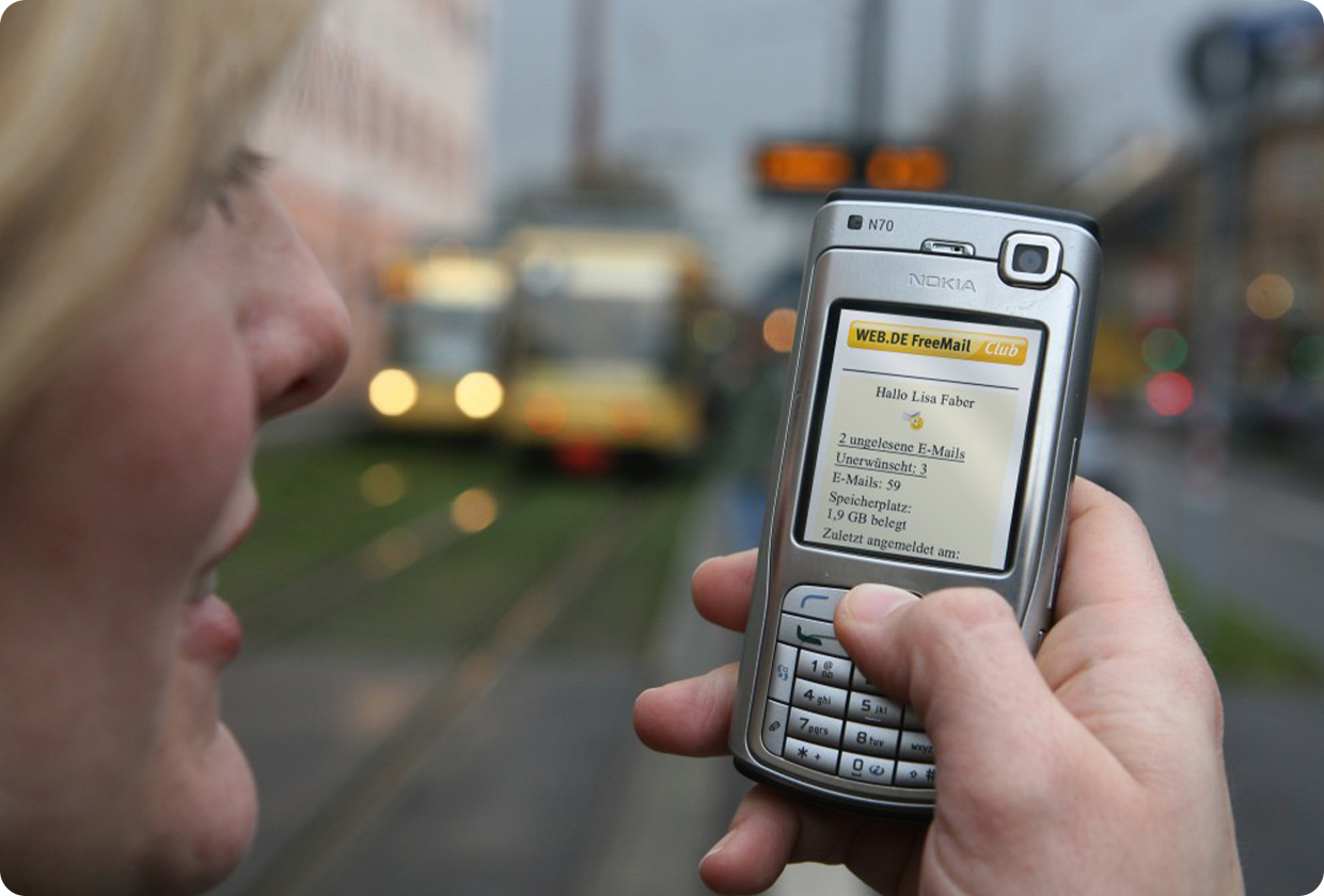 Frau hält ein Nokia Handy in der Hand, auf dem die mobile Version von WEB.DE zu sehen ist