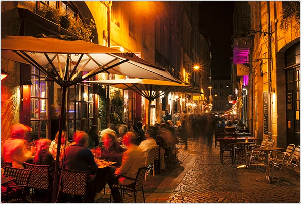 Bordeaux bei Nacht: Beleuchtete Straßenszenerie mit Gästen und Restauranttischen