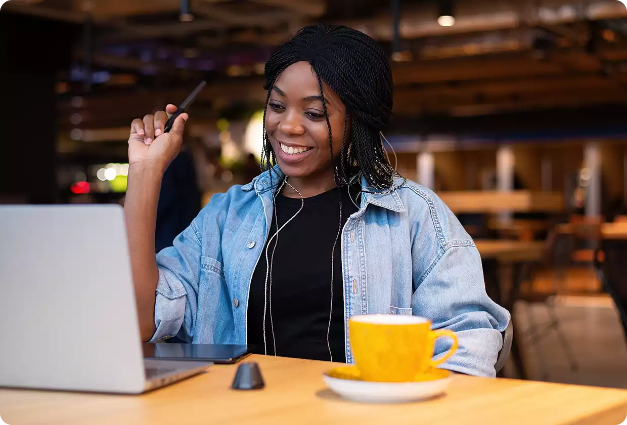 Junge lächelnde Frau, die vor ihrem Laptop sitzt.