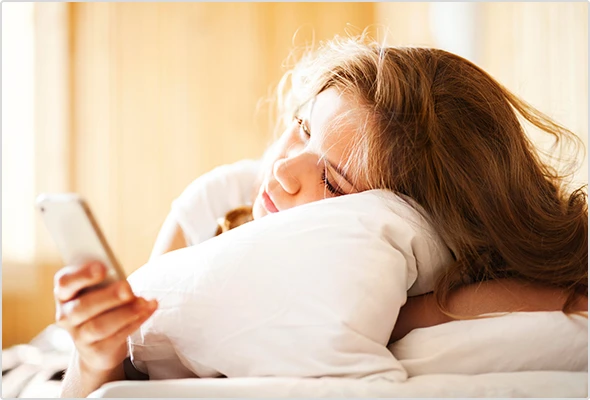 Junges Mädchen schaut betrübt auf ihr Smartphone.