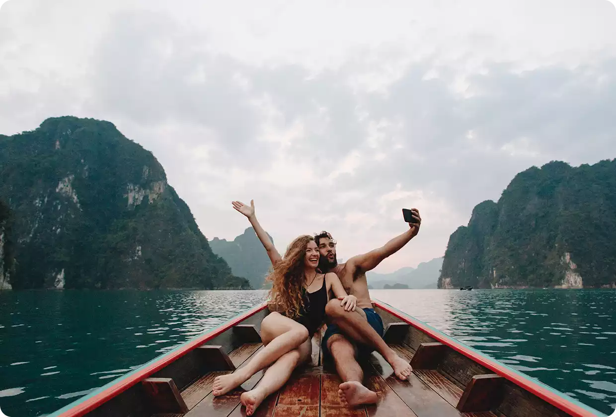 Pärchen sitzt im Boot auf einem Meer und schießt lächelnd ein Selfie von sich