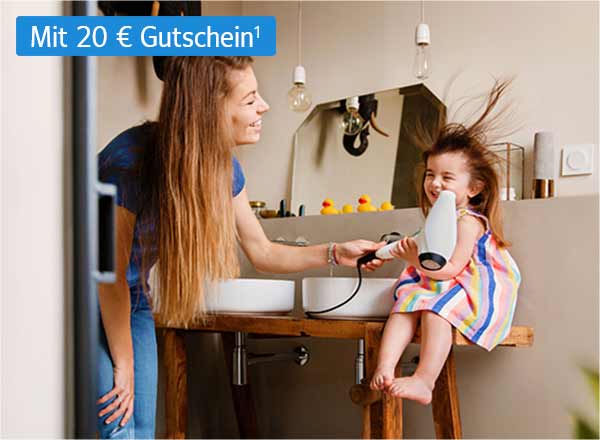 Eine Frau föhnt einem kleinen Mädchen in einem Badezimmer die Haare. Die Haare des Mädchens sind durch den Fön zerzaust. Beide lächeln fröhlich. Das Bild enthält eine Abbildung eines BestChoice-Gutscheins mit 20 Euro Gutscheinwert.