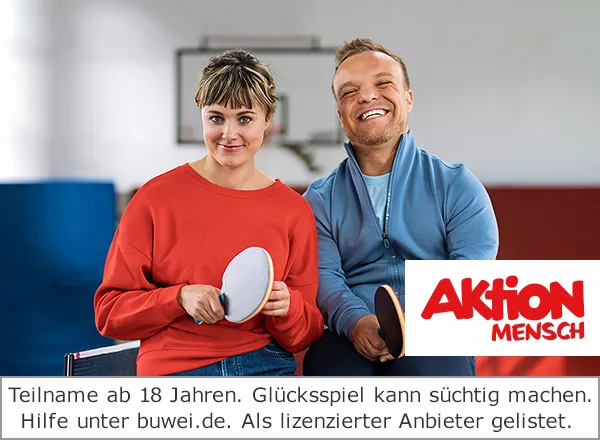 Eine Frau und ein Mann sitzen auf einer Tischtennisplatte nebeneinander und haben jeweils einen Tischtennisschläger in ihrer Hand. Im Hintergrund ist eine Sporthalle zu sehen.
