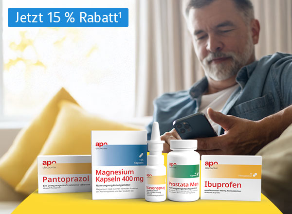 Arzneimittelpackungen auf einem Tisch, ein Mann sitzt auf einem Sofa und hält ein Smartphone.