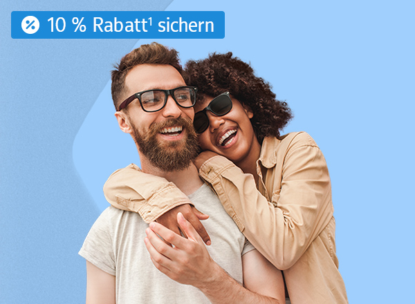 Ein Mann und eine Frau, welche beide lächeln und die Frau umarmt den Mann von Hinten seitlich. Der Mann trägt eine Brille mit einem schwarzen Rahmen und die Frau trägt eine schwarze Sonnenbrille.