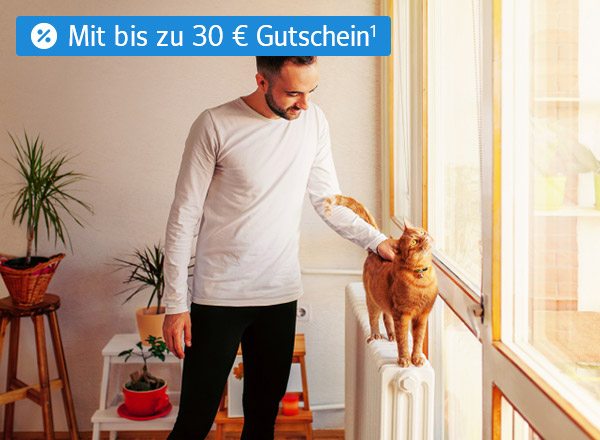 Ein Mann streichelt eine Katze, die auf einer Heizung steht. Im Hintergrund sind die Umrisse eines Wohnzimmers erkennbar.
