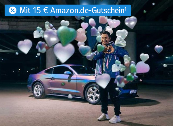 Mann steht neben silbernem Auto, umgeben von schwebenden Herz- und Sternsymbolen in verschiedenen Farben mit einem Text links oben der "+15 € Amazon.de Gutschein¹" lautet