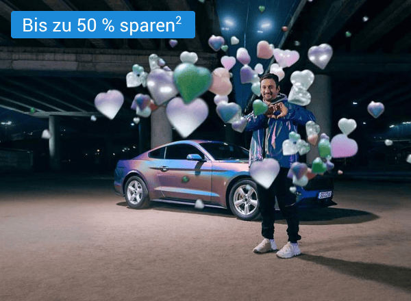 Mann steht neben silbernem Auto, umgeben von schwebenden Herz- und Sternsymbolen in verschiedenen Farben mit einem Text links oben der "+15 € Amazon.de Gutschein¹" lautet