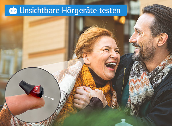 Ein grauhaariger Mann und eine rothaarige Frau sitzen lachend vor einem Haus. Der Mann hat die Frau im Arm. In einer Nahaufnahme ist ein Hörgerät zu sehen, das mit einem Pfeil auf das Ohr der Frau zeigt. Zudem wir in einem schriftlichen Hinweis darauf verwiesen, das man das beworben Hörgerät von proauris kostenlos testen kann.