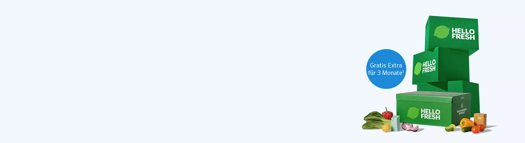 Drei grüne HelloFresh-Lieferboxen gestapelt mit einer weiteren Box im Vordergrund, daneben frisches Gemüse und Obst.