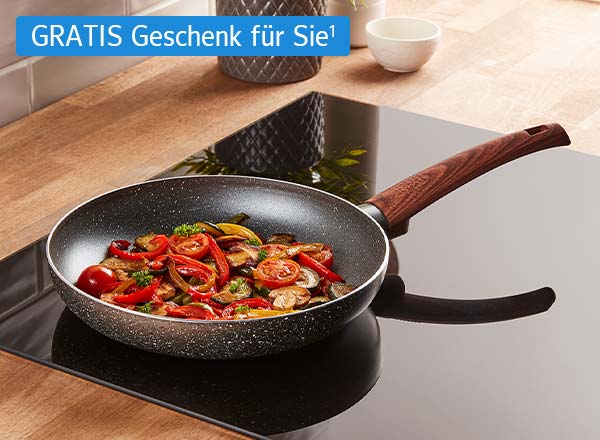 Bratpfanne mit Holzgriff auf Herd, gefüllt mit gebratenem Gemüse wie Tomaten, Paprika und Pilzen, dazu ein Chip mit dem Text: GRATIS Geschenk für Sie¹