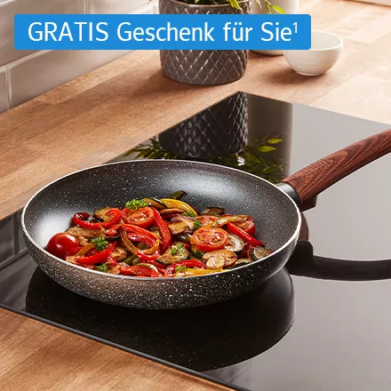 Bratpfanne mit Holzgriff auf Herd, gefüllt mit gebratenem Gemüse wie Tomaten, Paprika und Pilzen, dazu ein Chip mit dem Text: GRATIS Geschenk für Sie¹