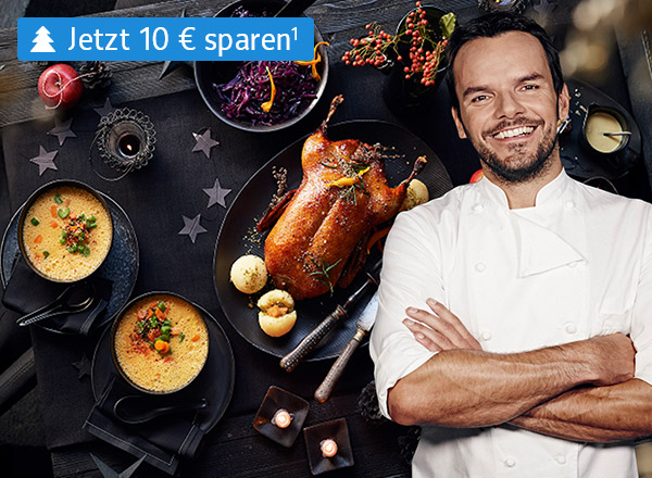 Festtagsmenü mit einer Ente lieght auf einem weihnachtlich dekorierten Tisch mit Steffen Henssler davor– Jetzt 10 € sparen!