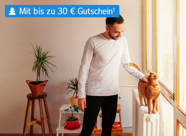 Ein Mann streichelt eine Katze, die auf einer Heizung steht. Im Hintergrund sind die Umrisse eines Wohnzimmers erkennbar.