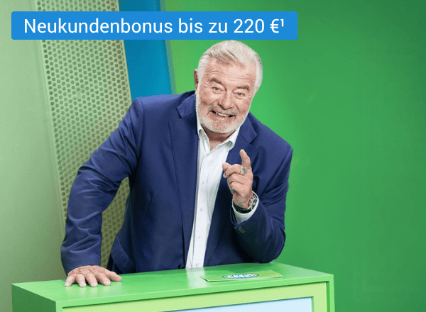 Älterer Mann im dunkelblauen Anzug stützt sich lachend auf grünes Pult und zeigt mit dem Zeigefinger auf sein Gegenüber.