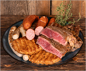 Grillteller mit verschiedenen Steaks, Würsten und Kräutern auf Holzuntergrund